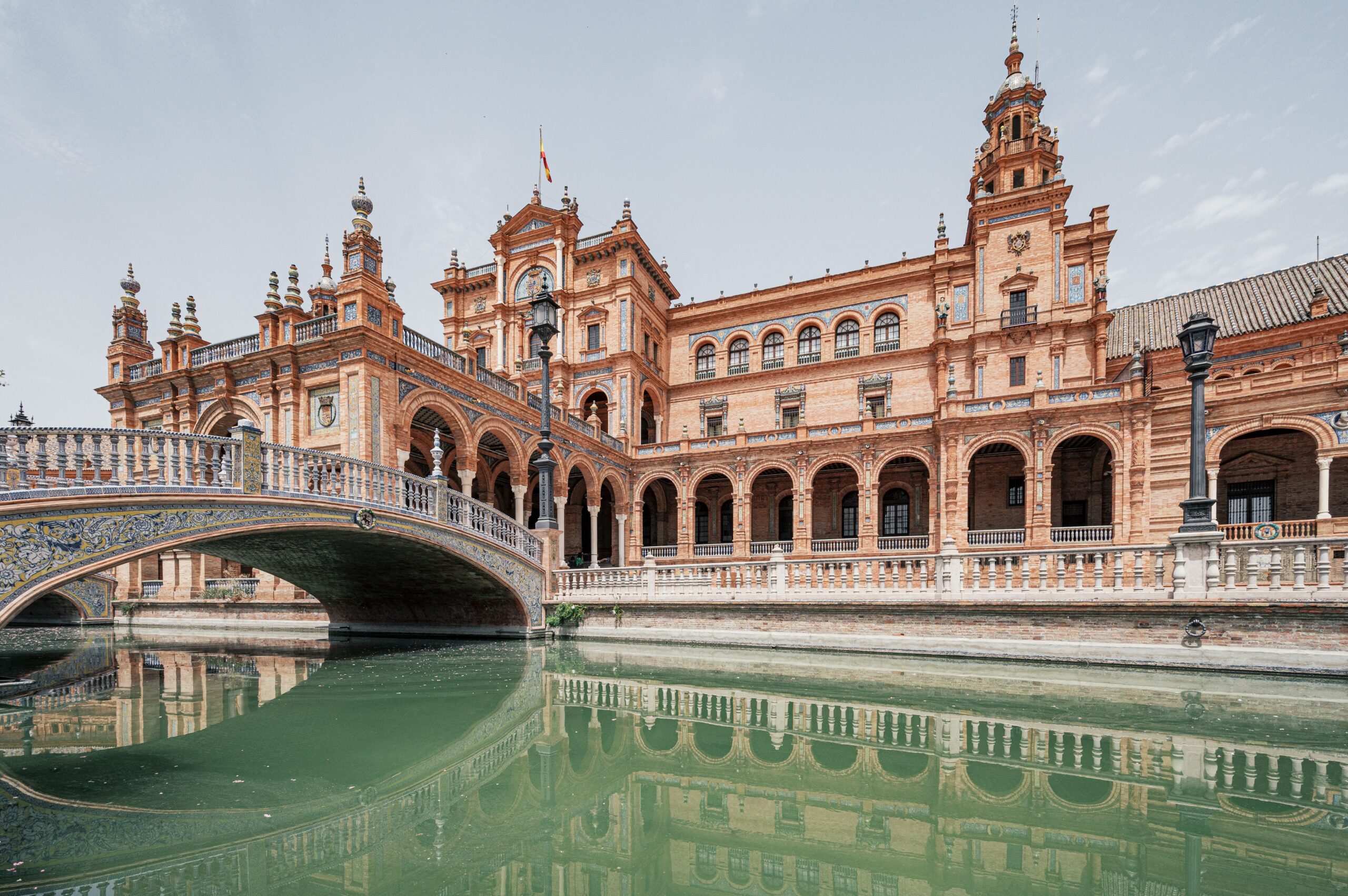 Beautiful Plaza de Espana palace with a bridge reflected in the water in Sevilla, Andalusia, Spain